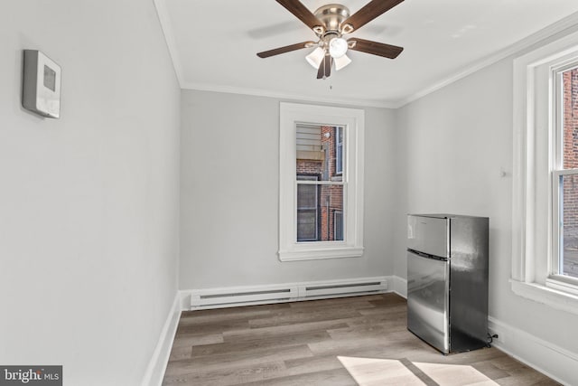 unfurnished room with ceiling fan, baseboard heating, crown molding, and light hardwood / wood-style flooring