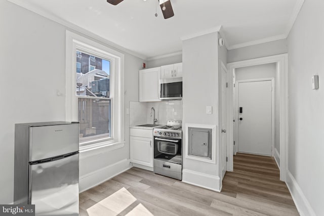 kitchen featuring a wealth of natural light, sink, stainless steel appliances, and white cabinetry