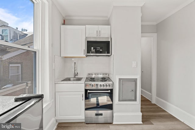 kitchen featuring sink, crown molding, white cabinetry, light hardwood / wood-style flooring, and appliances with stainless steel finishes