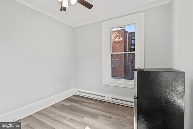 empty room with light hardwood / wood-style floors, baseboard heating, crown molding, and ceiling fan