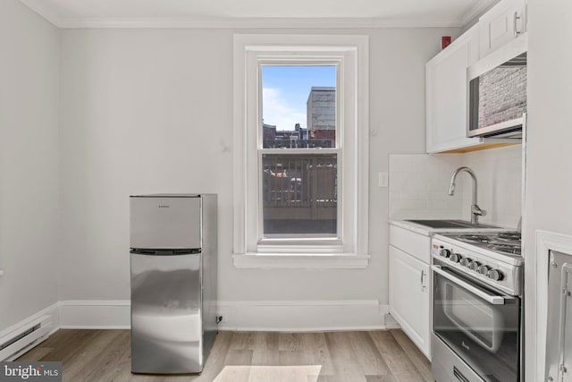 kitchen featuring light hardwood / wood-style floors, baseboard heating, white cabinets, and stainless steel appliances