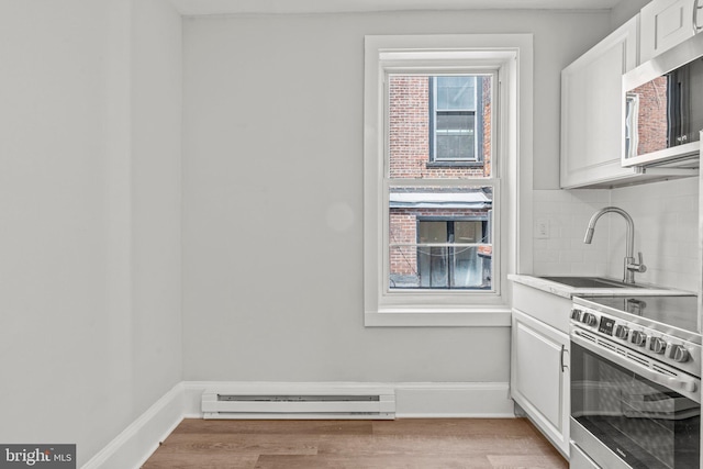 kitchen featuring white cabinetry, a baseboard heating unit, appliances with stainless steel finishes, tasteful backsplash, and light wood-type flooring