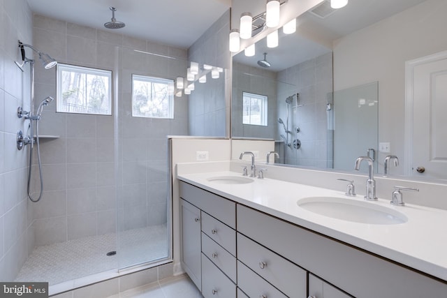 bathroom featuring a tile shower, vanity, tile patterned flooring, and plenty of natural light