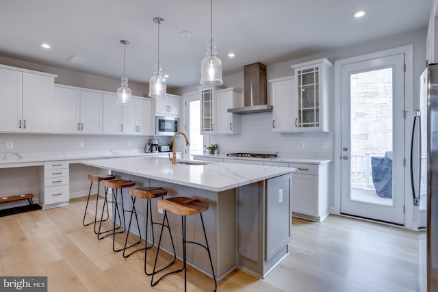 kitchen featuring built in microwave, white cabinetry, sink, and wall chimney exhaust hood