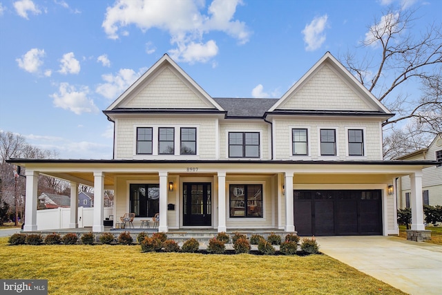 view of front of property featuring a garage, a front yard, and covered porch