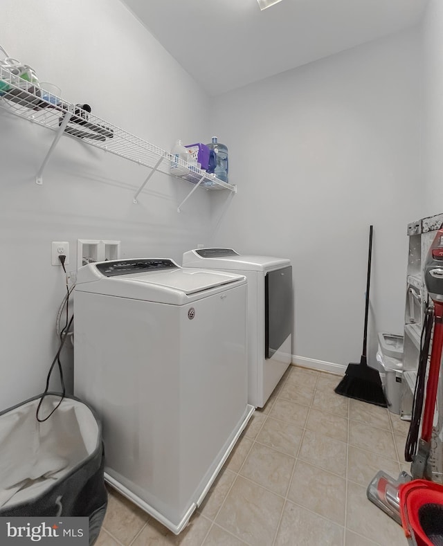 clothes washing area with independent washer and dryer and light tile patterned floors