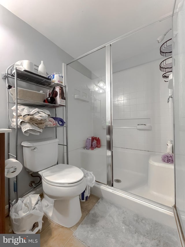 bathroom featuring tile patterned floors, toilet, and a shower with shower door