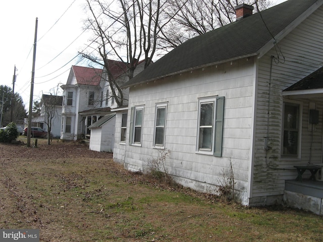 view of home's exterior with a shingled roof and a chimney