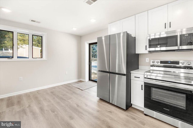 kitchen with a healthy amount of sunlight, white cabinetry, light hardwood / wood-style floors, and appliances with stainless steel finishes