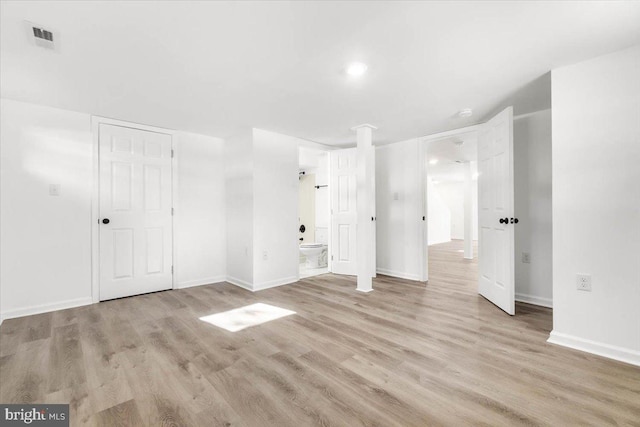 unfurnished bedroom with light hardwood / wood-style floors and connected bathroom