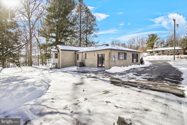 snow covered back of property featuring central air condition unit