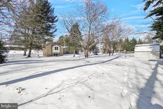 snowy yard featuring a storage shed