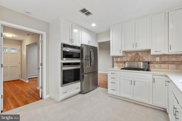 kitchen featuring stainless steel appliances, white cabinetry, tasteful backsplash, and a baseboard radiator