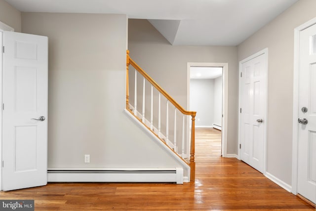 staircase featuring hardwood / wood-style floors and a baseboard heating unit