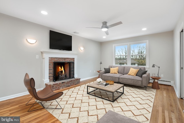 living room with light wood-type flooring, a brick fireplace, and baseboard heating