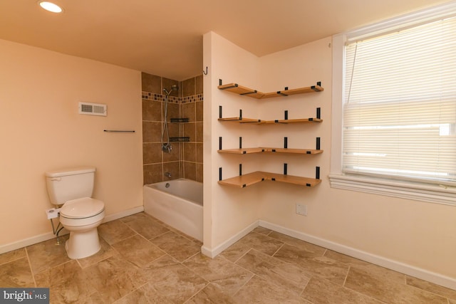 bathroom with toilet and tiled shower / bath combo