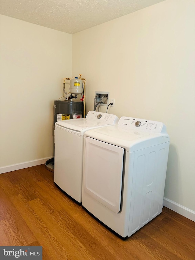 laundry area featuring separate washer and dryer, a textured ceiling, water heater, and light wood-type flooring