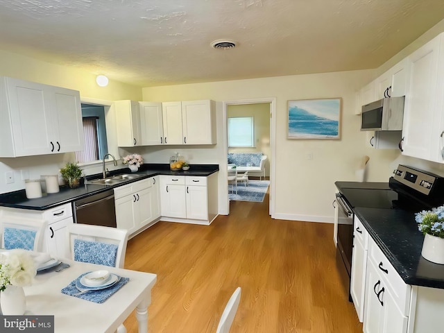 kitchen featuring white cabinets, appliances with stainless steel finishes, sink, and light wood-type flooring