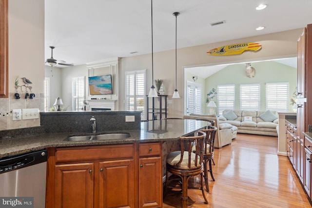 kitchen with sink, a wealth of natural light, dishwasher, and dark stone countertops