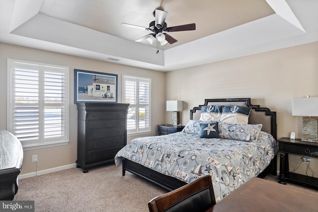 carpeted bedroom featuring ceiling fan and a tray ceiling