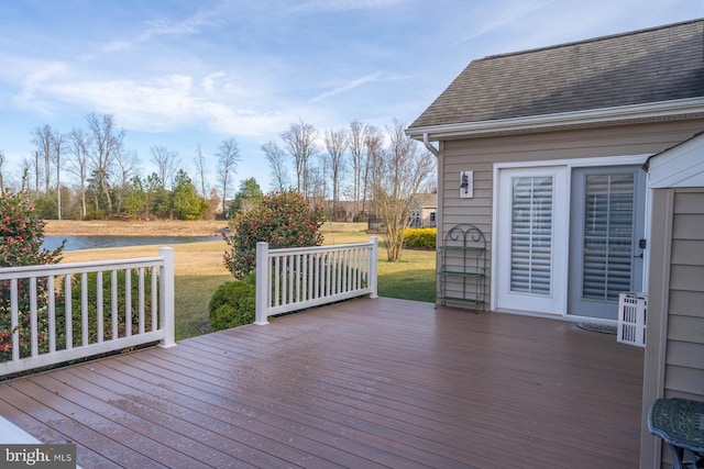 wooden terrace featuring a lawn and a water view