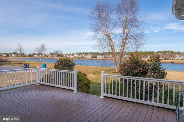 wooden terrace with a water view and a lawn