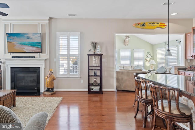 dining room with vaulted ceiling, a healthy amount of sunlight, and hardwood / wood-style flooring