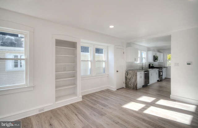 kitchen with plenty of natural light, white cabinets, light hardwood / wood-style flooring, and stainless steel appliances