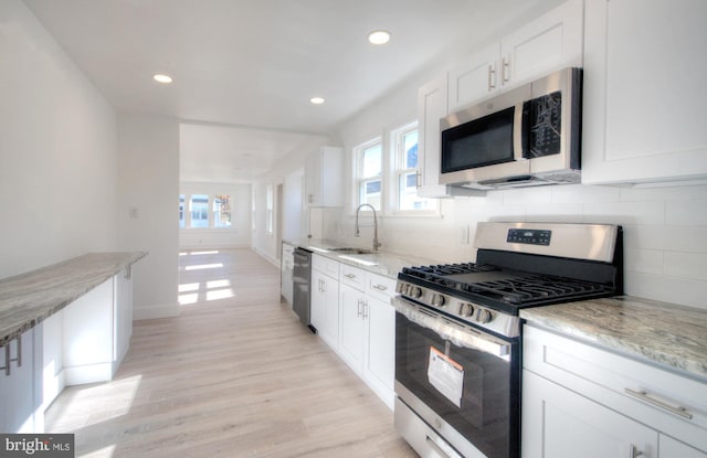 kitchen featuring a wealth of natural light, white cabinets, appliances with stainless steel finishes, and sink