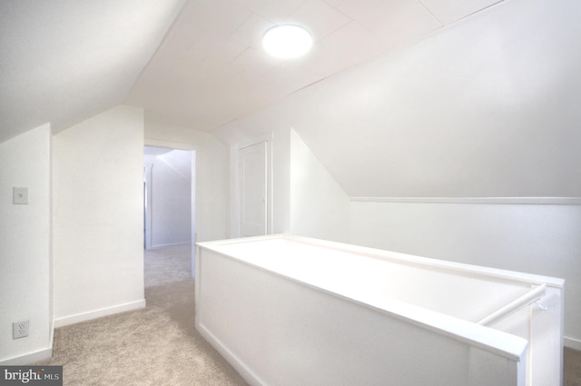 hallway featuring light colored carpet and vaulted ceiling