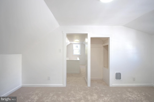 additional living space with light carpet and vaulted ceiling