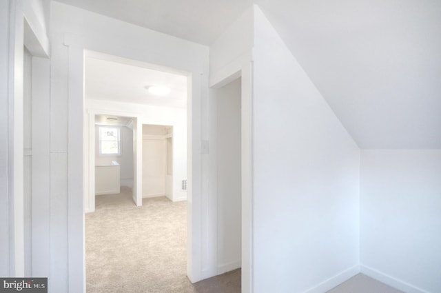 hallway featuring light carpet and vaulted ceiling