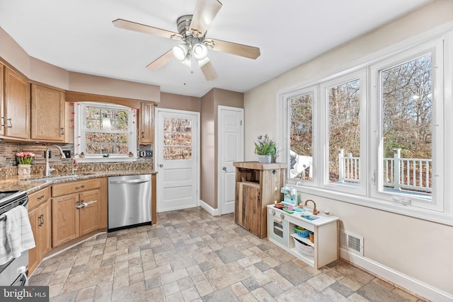 kitchen featuring appliances with stainless steel finishes, sink, backsplash, ceiling fan, and light stone counters