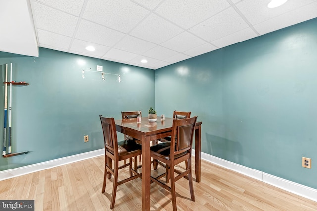 dining room with light hardwood / wood-style floors and a drop ceiling