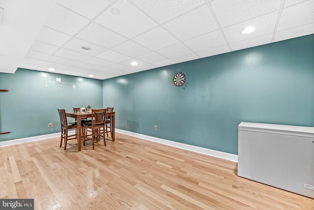 dining room with light hardwood / wood-style floors and a drop ceiling