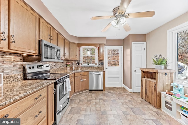 kitchen with tasteful backsplash, light stone countertops, plenty of natural light, and stainless steel appliances