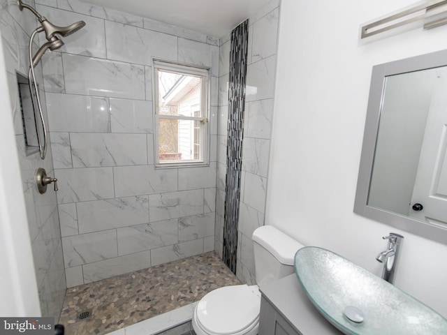 bathroom featuring tiled shower, vanity, and toilet