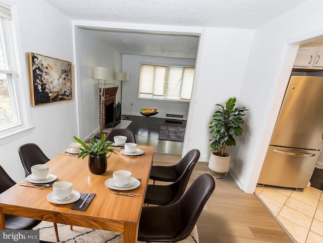 tiled dining room featuring a textured ceiling and a fireplace