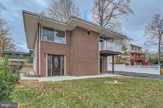 view of front of house featuring a balcony and a front yard