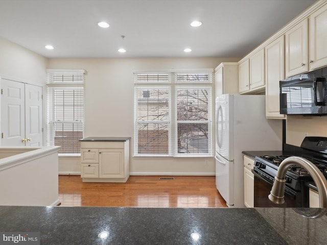 kitchen featuring black appliances, a wealth of natural light, light hardwood / wood-style flooring, and cream cabinetry