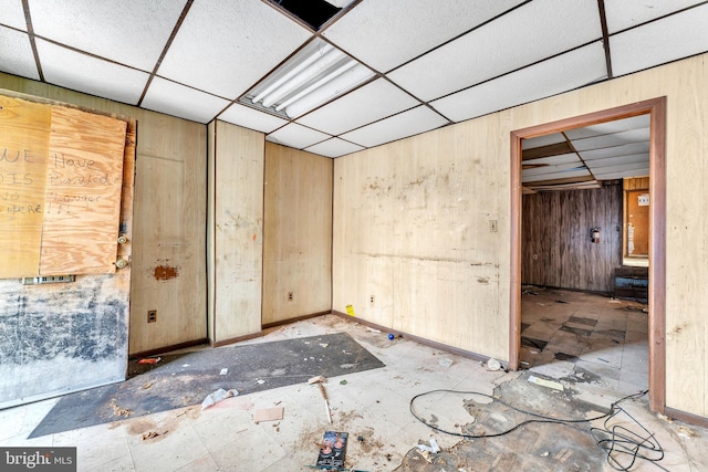 spare room with a paneled ceiling and wooden walls