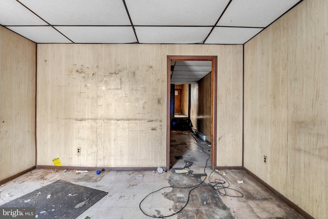 spare room featuring wooden walls and a drop ceiling