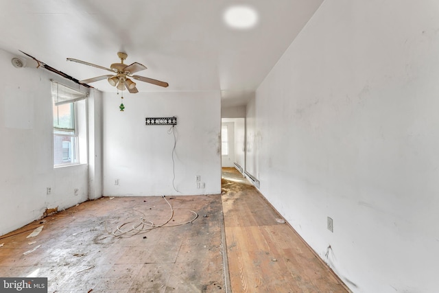 empty room featuring ceiling fan and a baseboard heating unit