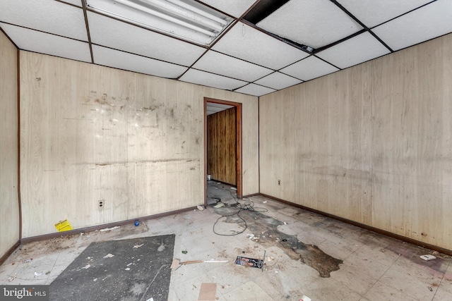 empty room with a paneled ceiling and wooden walls