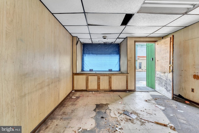 miscellaneous room with a paneled ceiling and wooden walls