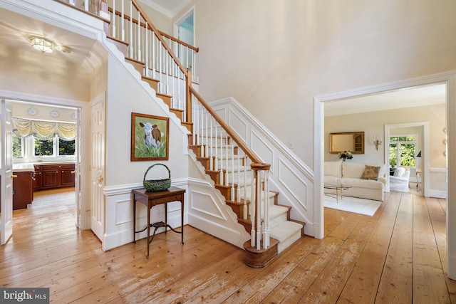 stairway featuring crown molding, wood-type flooring, and a high ceiling