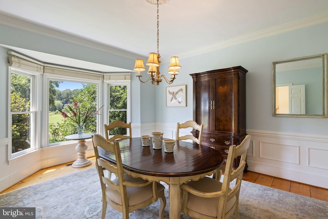 dining area with ornamental molding, an inviting chandelier, and light hardwood / wood-style floors