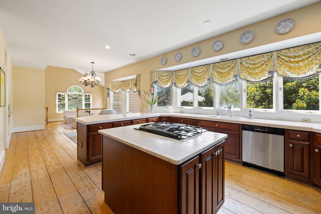 kitchen with sink, decorative light fixtures, stainless steel dishwasher, a kitchen island, and black gas cooktop