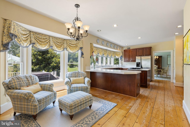 kitchen with sink, a chandelier, kitchen peninsula, stainless steel refrigerator with ice dispenser, and light wood-type flooring