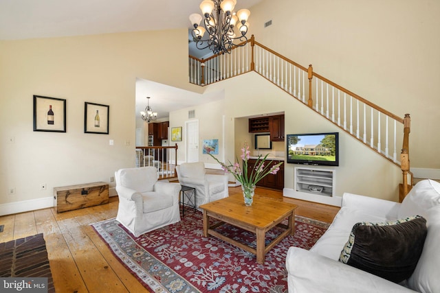 living room with a chandelier, light hardwood / wood-style floors, and a high ceiling